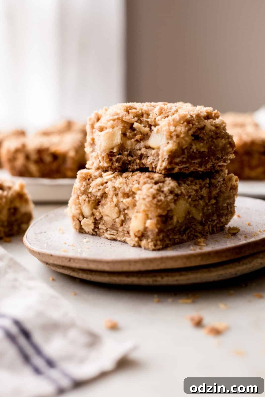 Golden Apple Crumble Bars 11 bite missing out of a bar on a stack of bars and plates