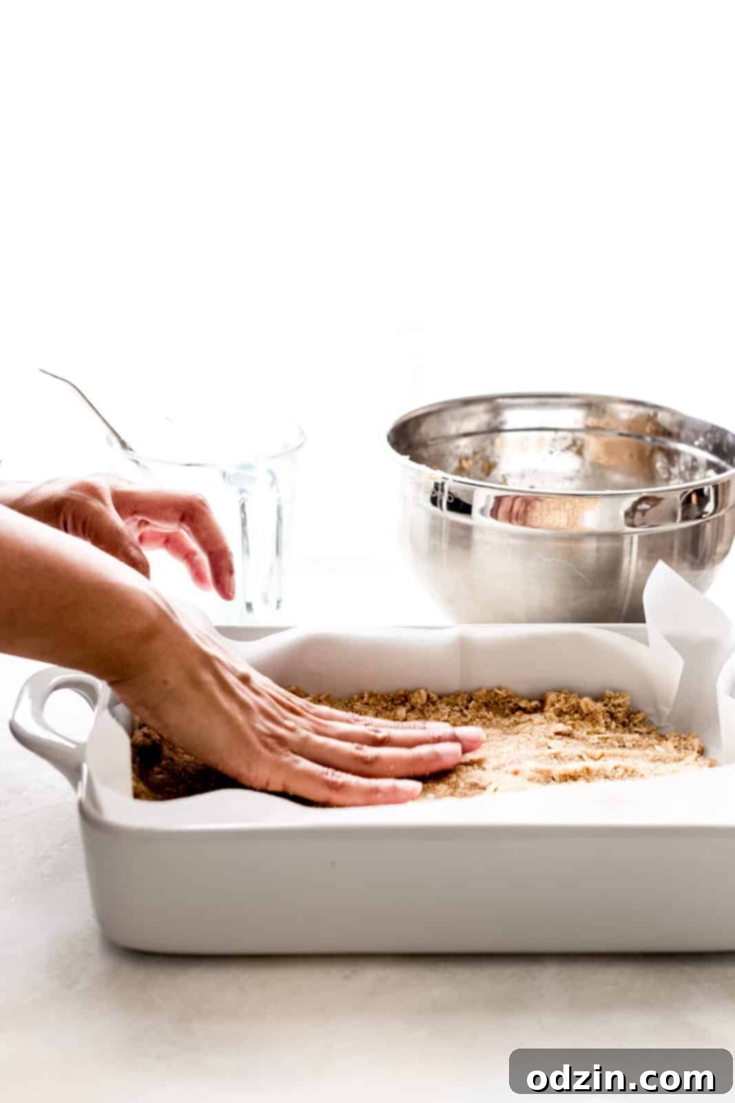 Golden Apple Crumble Bars 6 hand pressing bar crust in white baking dish