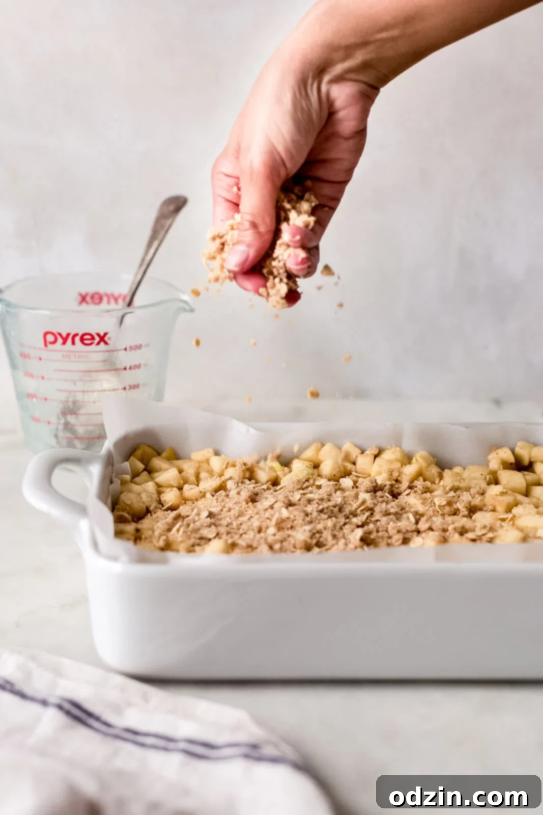 Golden Apple Crumble Bars 8 sprinkling crumble mixture over diced apples in white baking dish