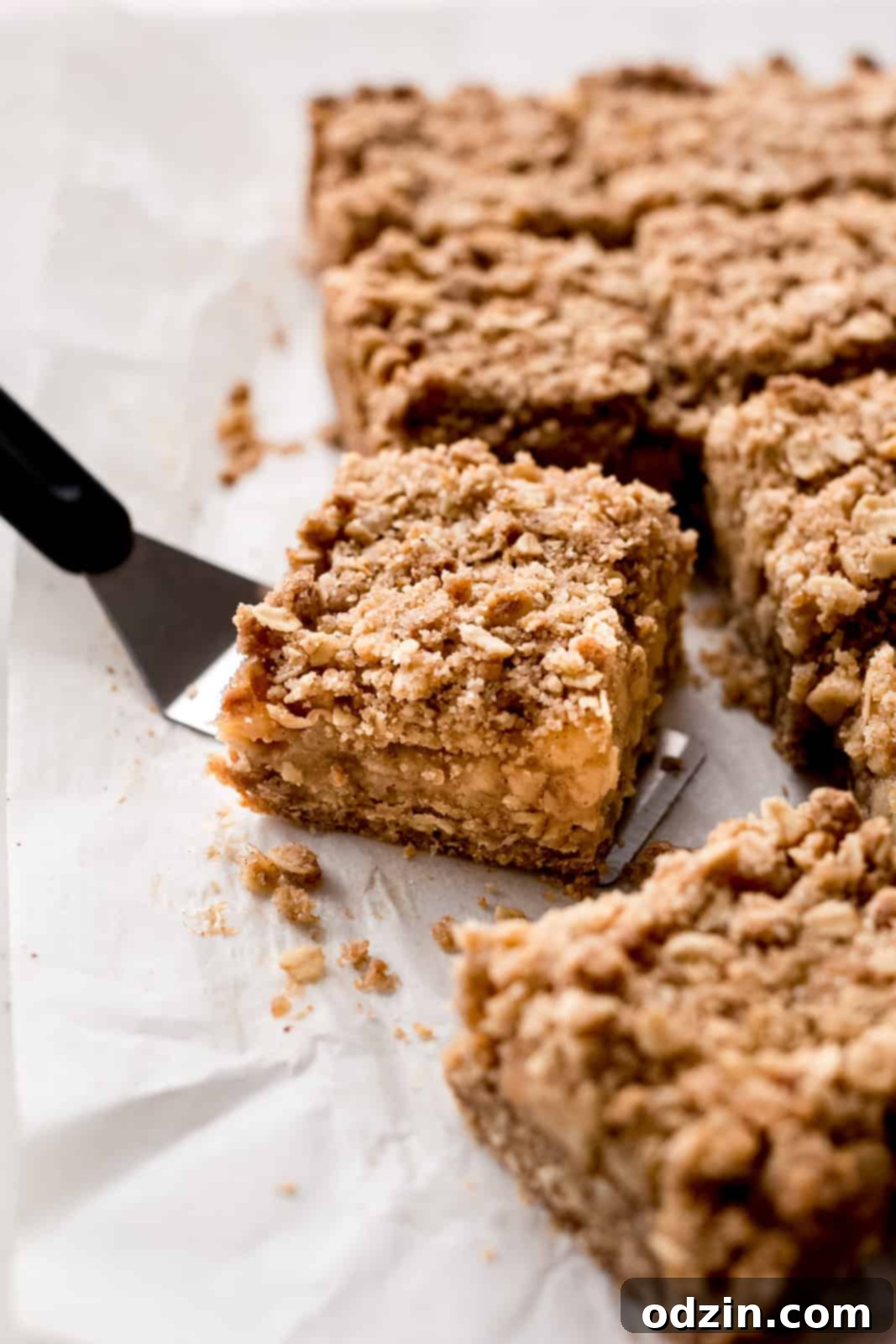 Golden Apple Crumble Bars 9 a crumble bar on spatula on white parchment paper
