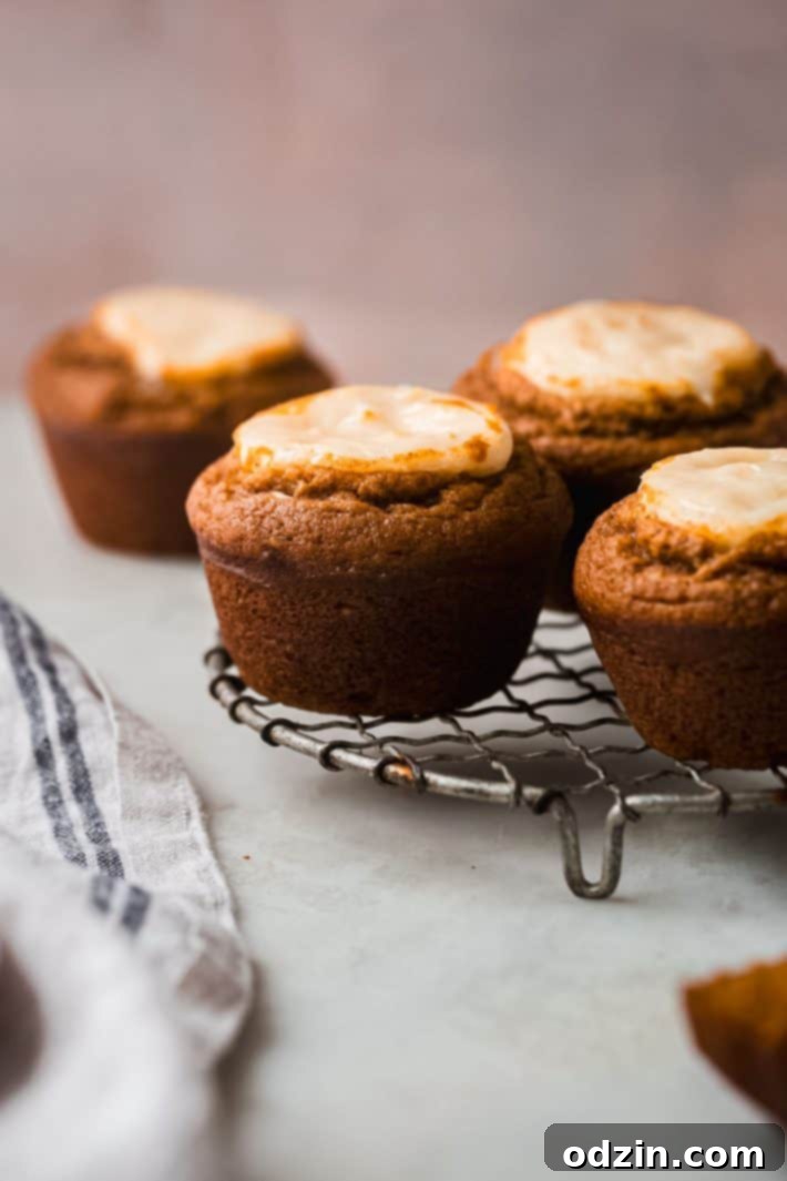Chai-Spiced Pumpkin Cream Cheese Muffins 8 Freshly baked muffins cooling on a wire rack, steam gently rising.