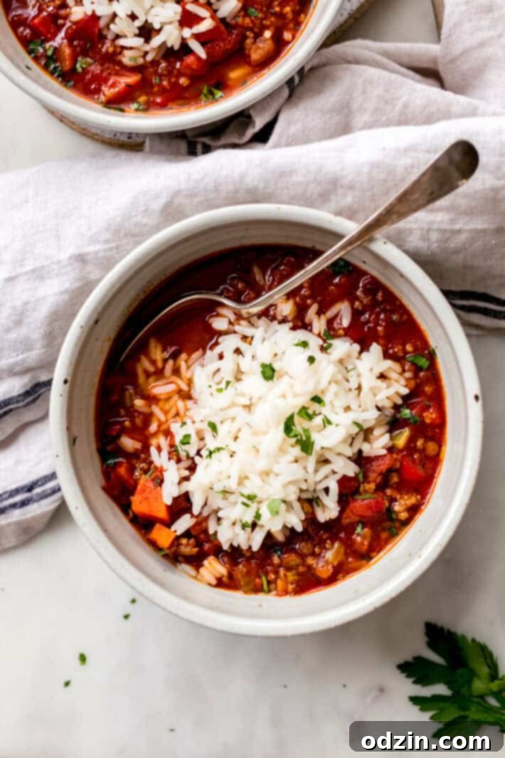 speckled bowl of soup with rice on top and spoon resting in bowl on white marble