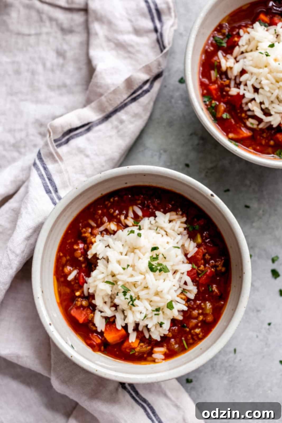 bowls of moroccan stuffed pepper soup on grey surface with a dollop of rice and parsley on top
