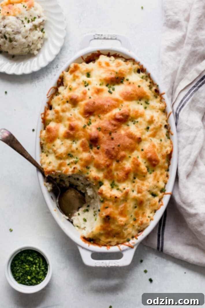 Creamy twice-baked potato casserole in a white dish with a serving spoon on a pristine white surface, ready to be enjoyed.