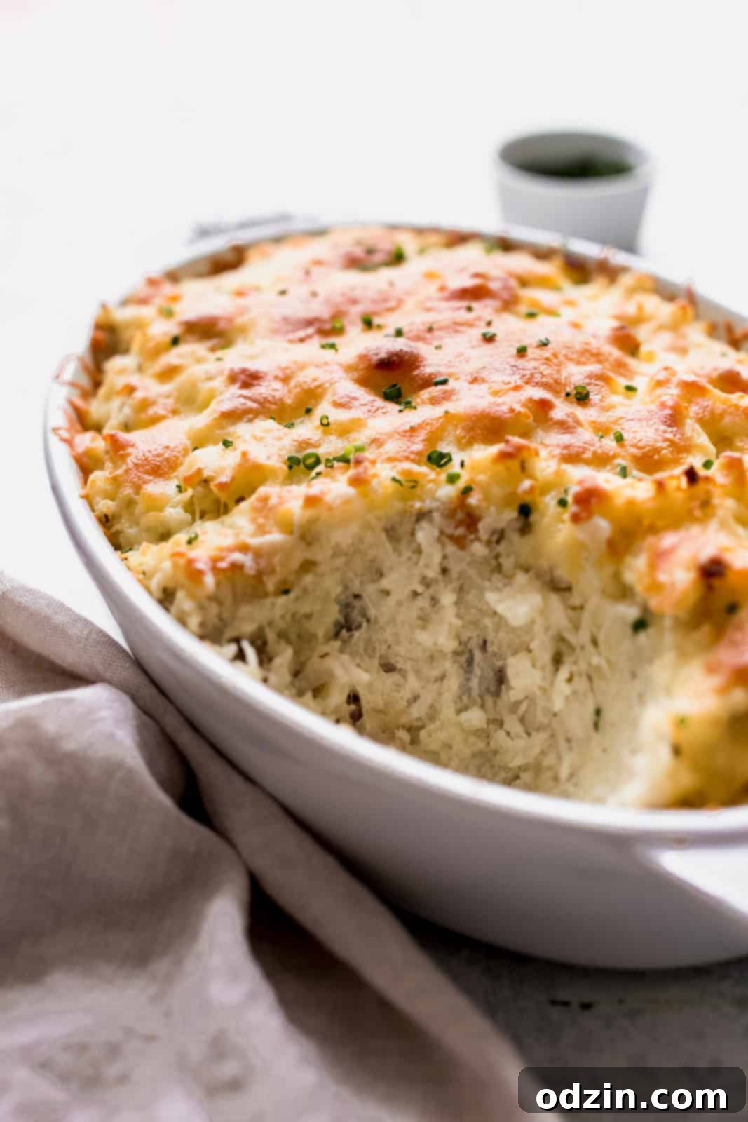 Close-up side view of Potatoes Romanoff in a casserole dish, revealing its creamy, fluffy interior texture and golden-brown topping.