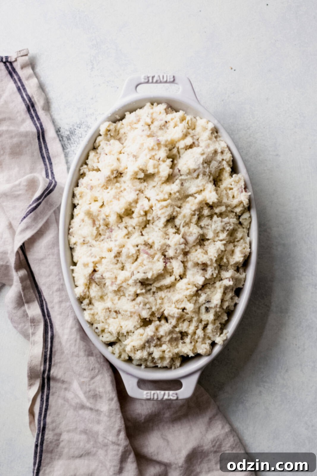 A white baking dish filled with fluffy, seasoned twice-baked potatoes, perfectly prepped and awaiting their final bake in the oven.
