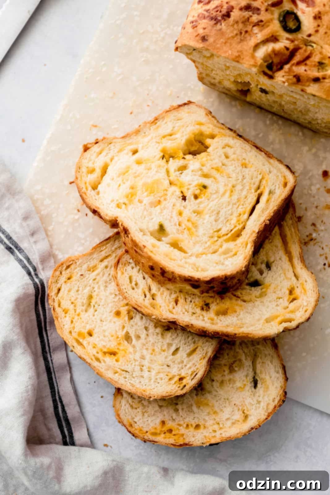 Spicy Cheddar Jalapeño Loaf 2 slices of jalapeno cheddar bread on cutting board with tea towel
