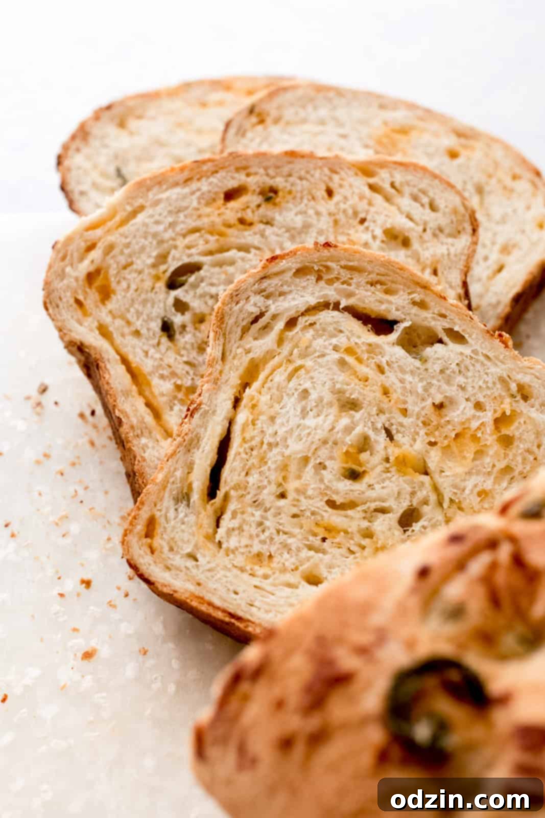Spicy Cheddar Jalapeño Loaf 3 slices of cheddar bread on speckled white cutting board