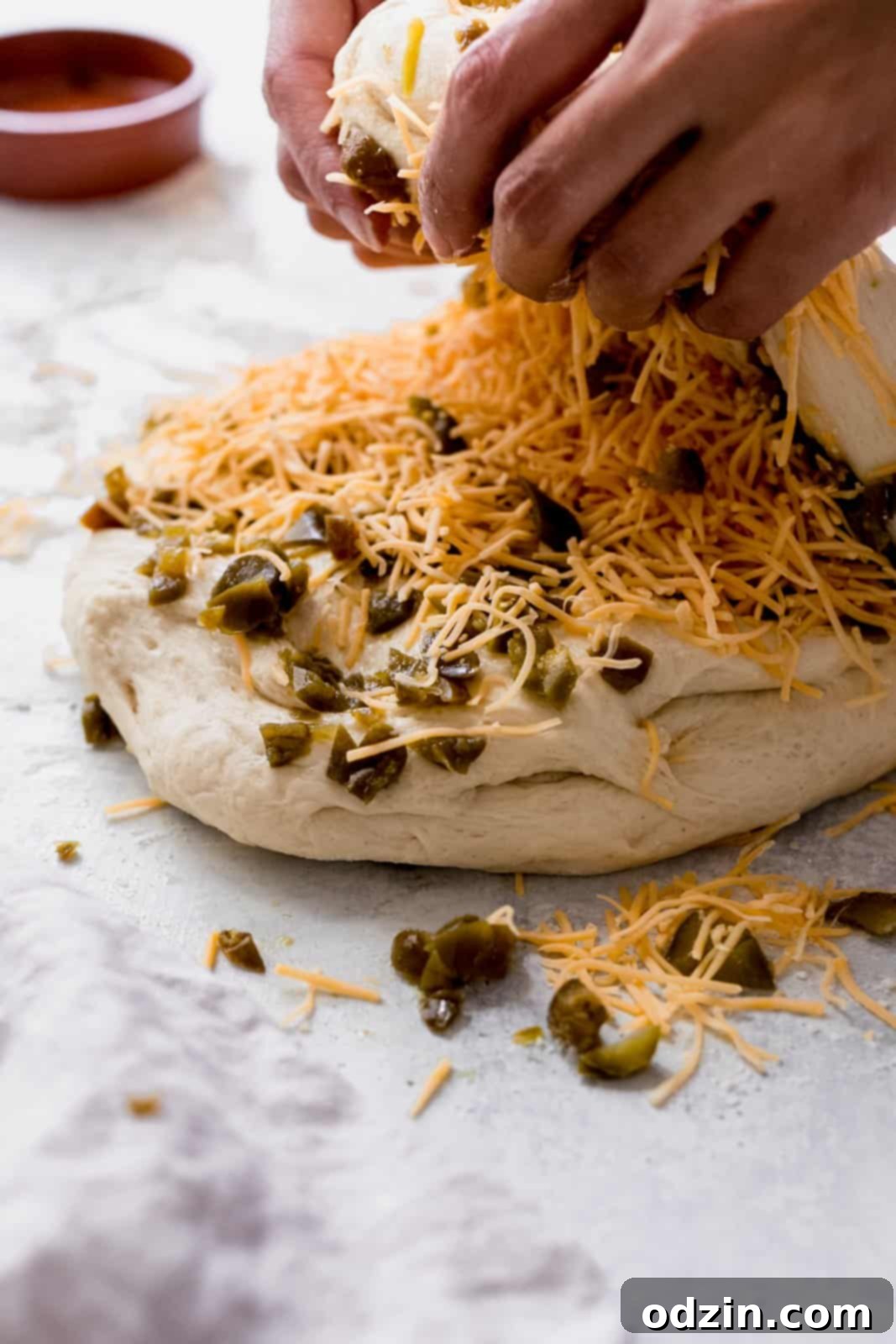 Spicy Cheddar Jalapeño Loaf 8 hands folding jalapeños and cheese into the bread