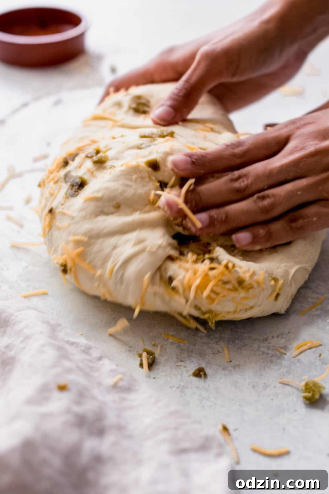 Spicy Cheddar Jalapeño Loaf 9 hands rolling and incorporating ingredients into bread dough
