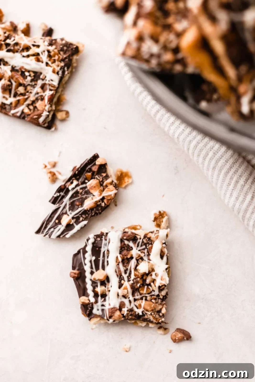 close up of saltine bark covered in toffee and chocolate drizzle on grey surface