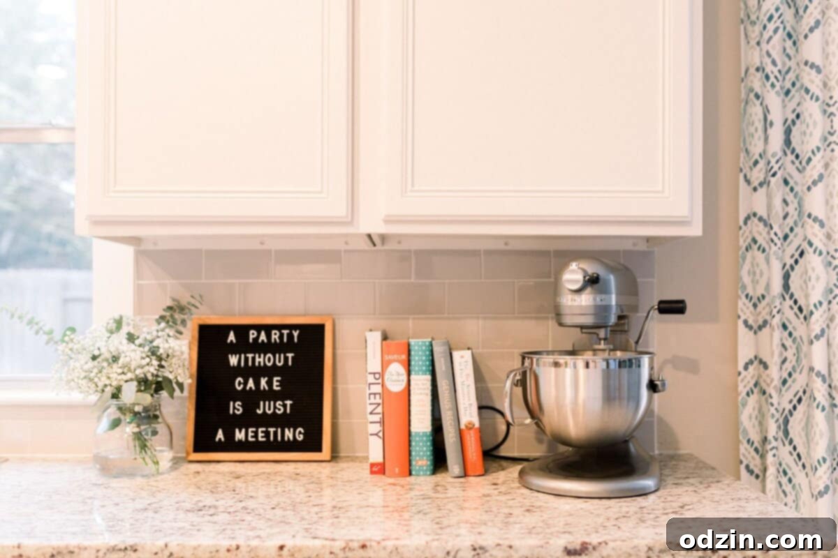 A beautifully styled kitchen scene featuring cookbooks, a stand mixer, and a charming sign that reads 'A party without cake is just a meeting'.