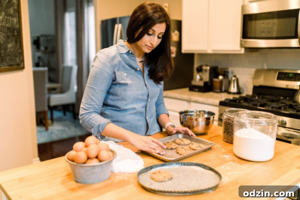 Close-up of the author moving freshly baked, warm cookies from a baking sheet onto an elegant serving dish.