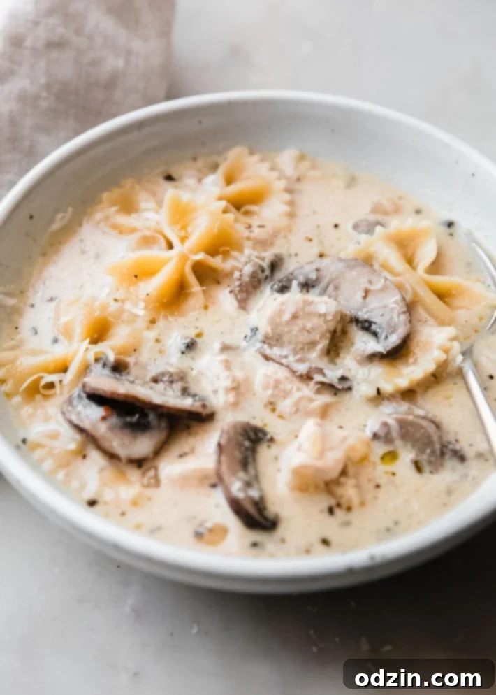 Bowl of creamy Roasted Garlic White Chicken Lasagna Soup with chicken, mushrooms, and pasta