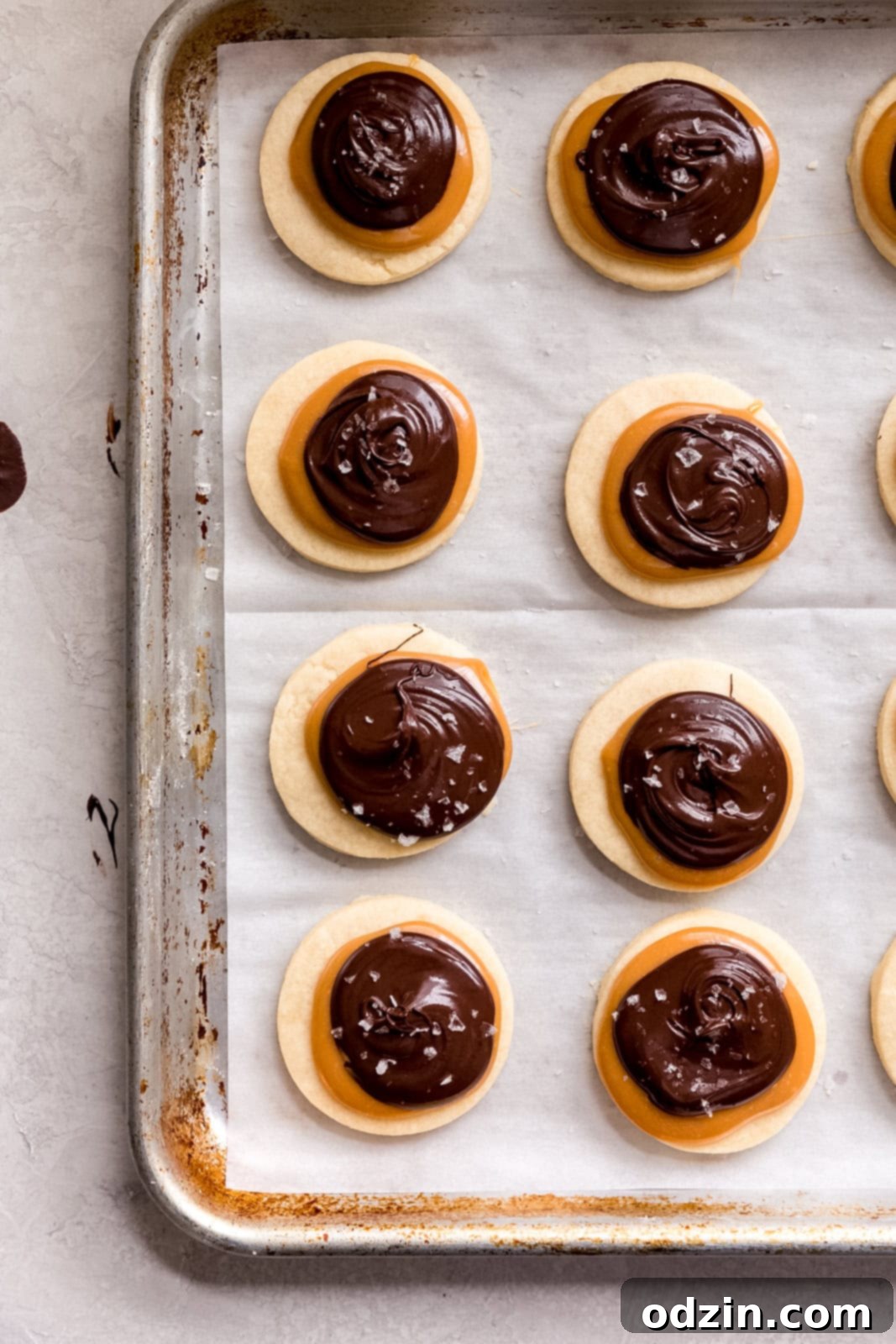 Copycat Twix Shortbread Cookies 6 shortbread cookies topped with caramel and chocolate dollops on sheet pan