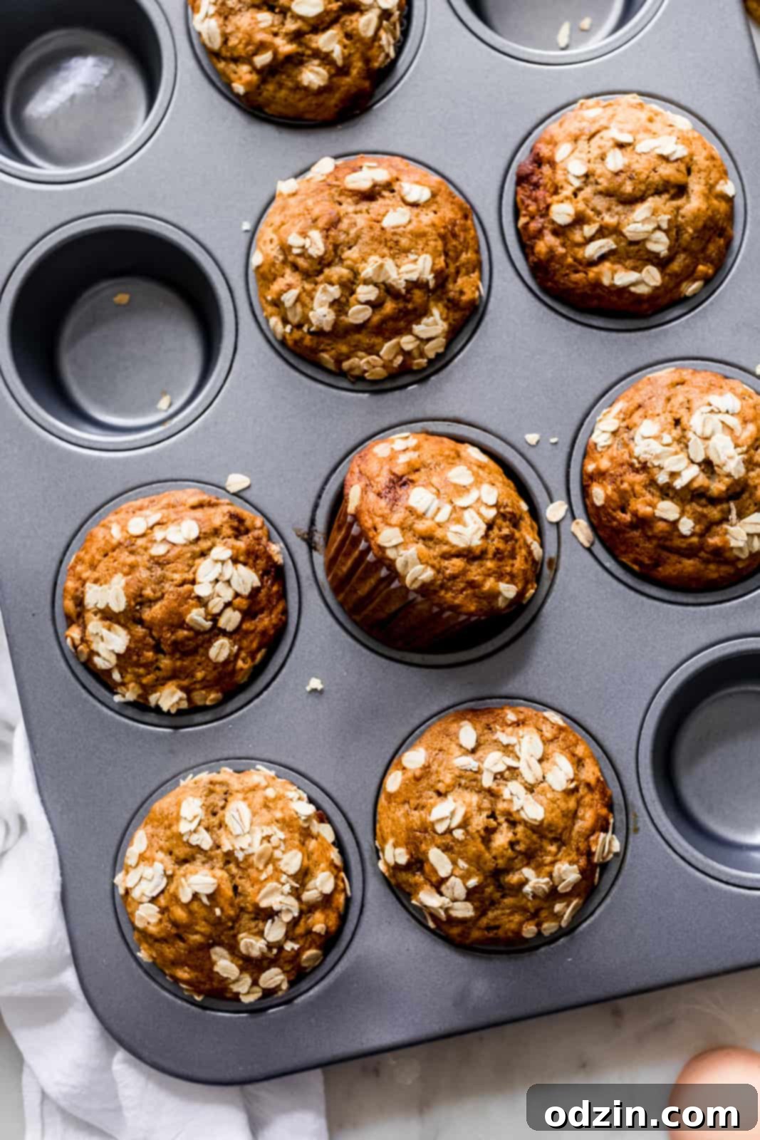 muffin pan with prepared muffins topped with rolled oats