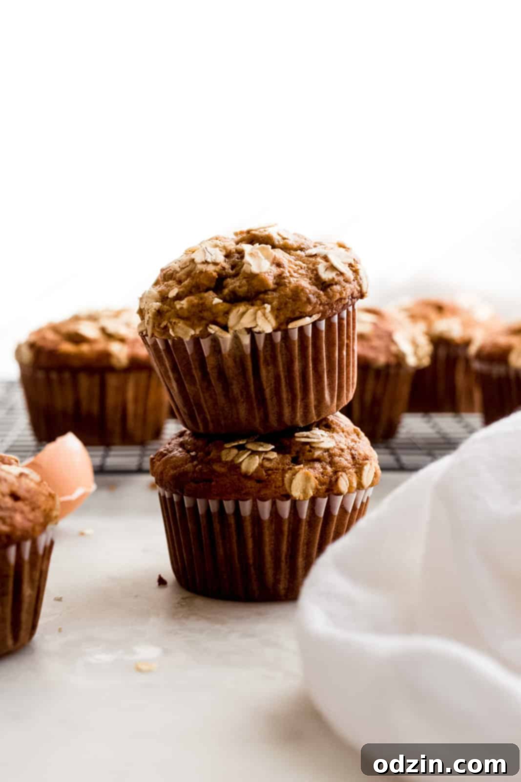 stack of two banana nut muffins with more muffins on wire rack in the back