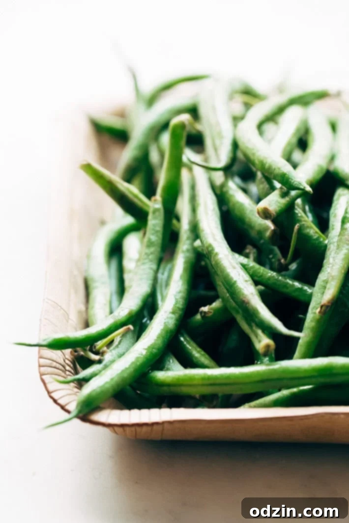 Fresh, vibrant green beans neatly arranged on a rustic cardboard tray, ready for preparation