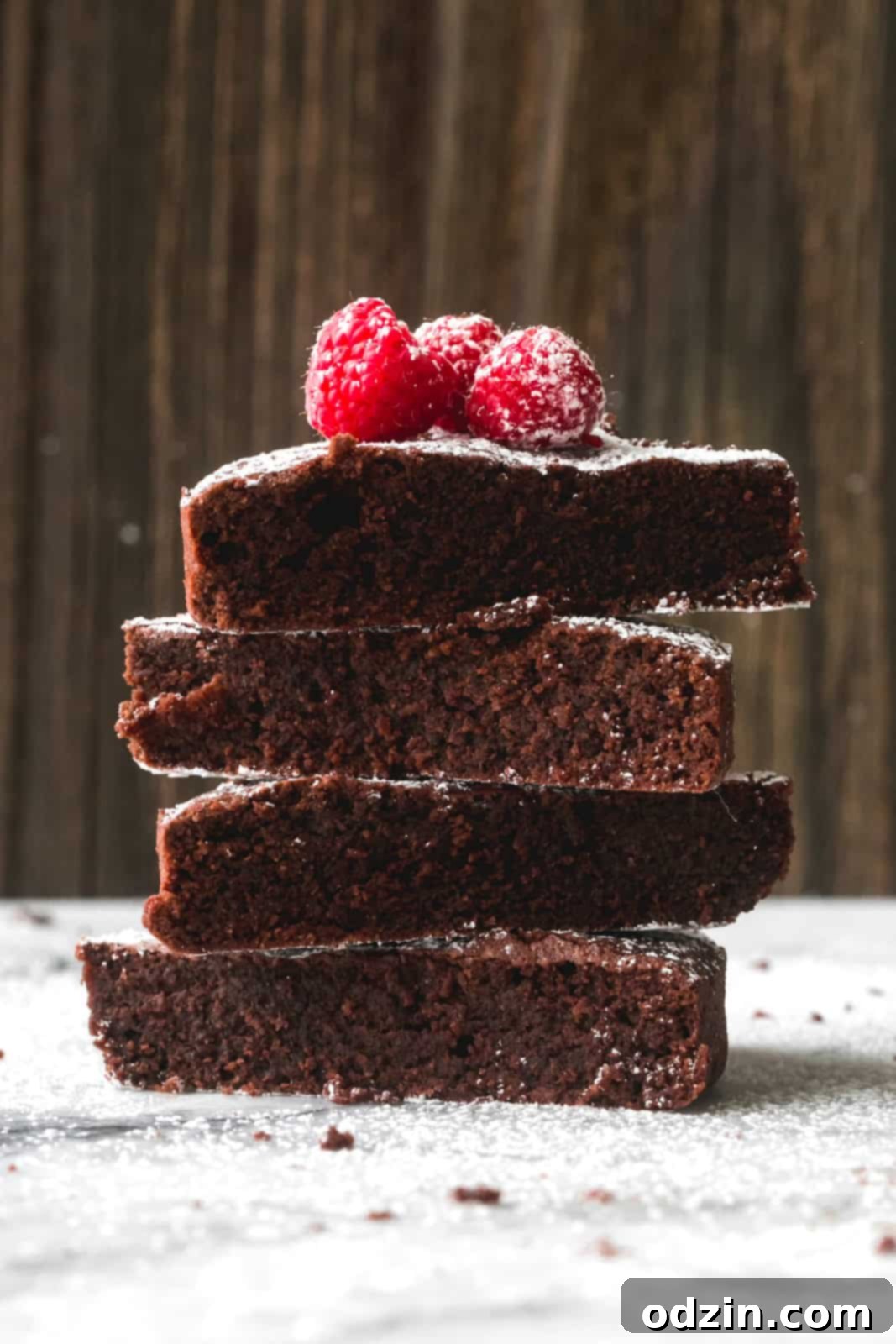 Caprese Flourless Chocolate Cake 4 stack of Caprese cake slices dusted with powdered sugar and topped with fresh raspberries