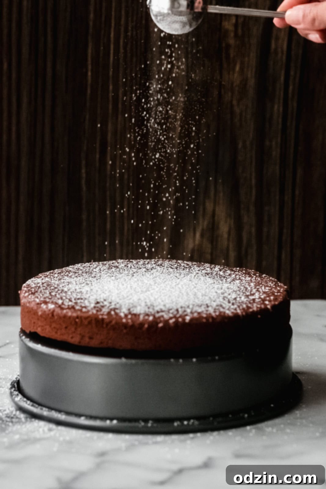 Caprese Flourless Chocolate Cake 7 dusting prepared Torta Caprese with powdered sugar from a sugar wand