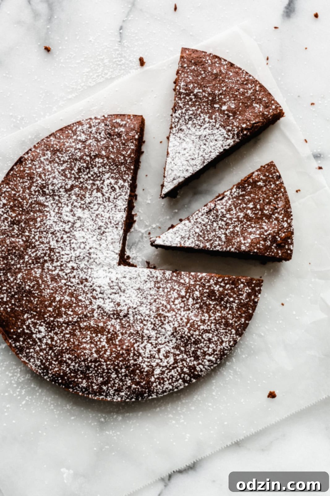 Caprese Flourless Chocolate Cake 8 prepared flourless chocolate cake on parchment paper dusted with powdered sugar with two slices cut out