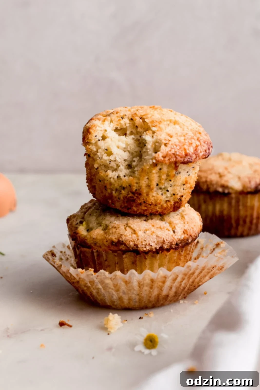 Freshly Baked Lemon Zucchini Muffins 8 stack of two lemon muffins with a bite taken out of the one on top