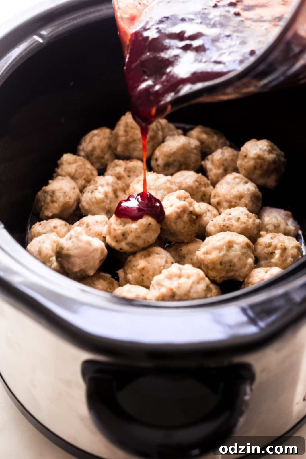 Sticky Honey Chipotle Slow Cooker Meatballs 5 slow cooker loaded with cooked meatballs being drizzled with bbq honey chipotle sauce
