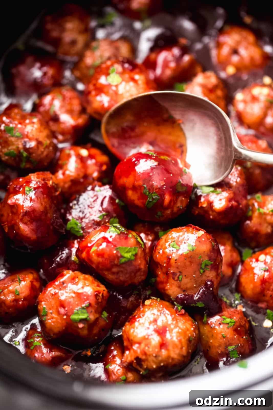 Sticky Honey Chipotle Slow Cooker Meatballs 7 spoon lifting sauced chicken meatball from slow cooker