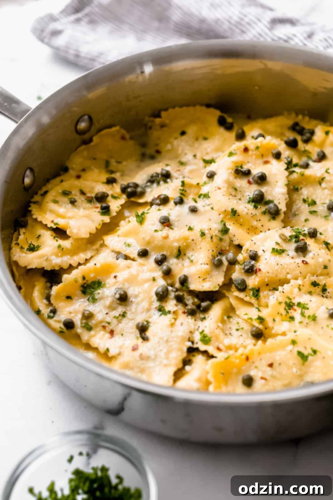 saute pan showing side shot of ravioli in piccata sauce