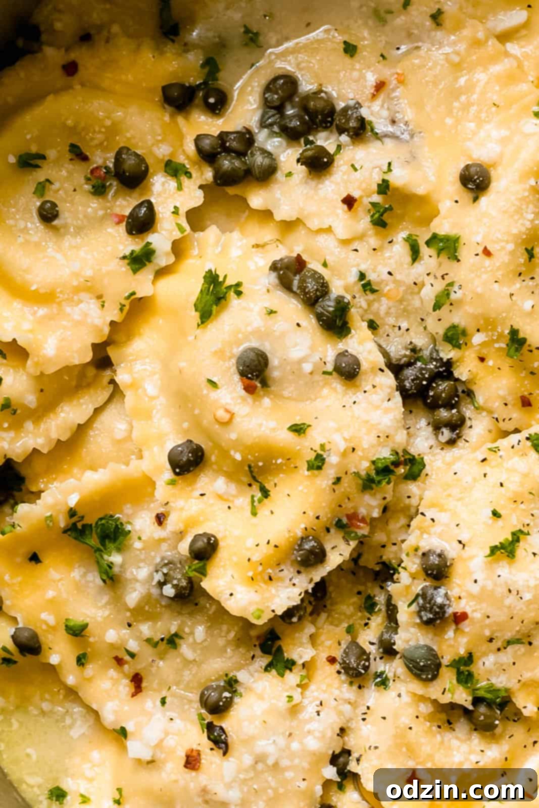 close up shot showing texture of ravioli in lemon butter sauce sprinkled with capers and parmesan cheese