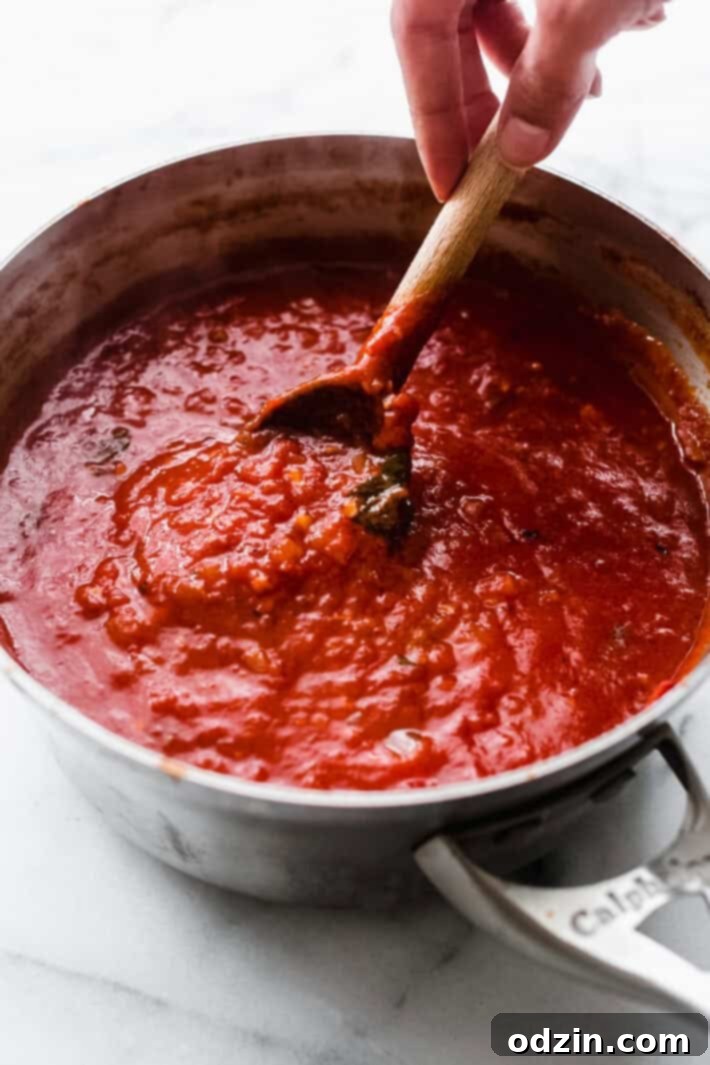 Arrabbiata Sauce in sauce pot being lifted by wooden spoon