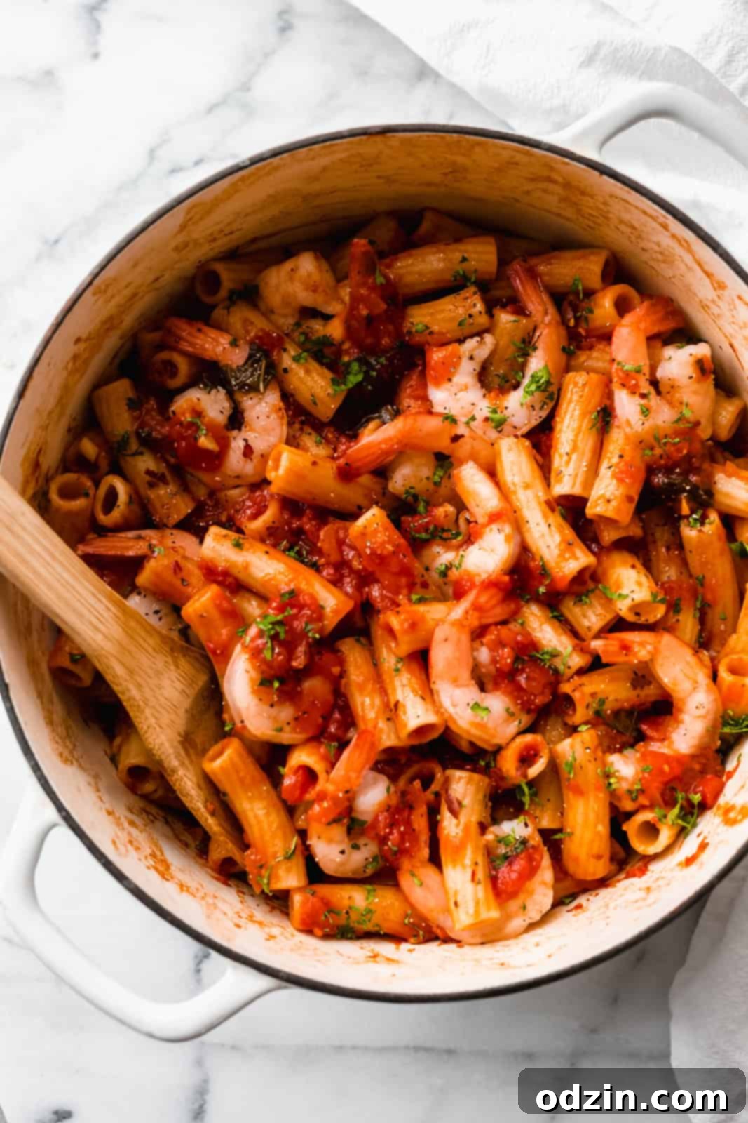 white cast iron pot with prepared pasta with shrimp and sauce