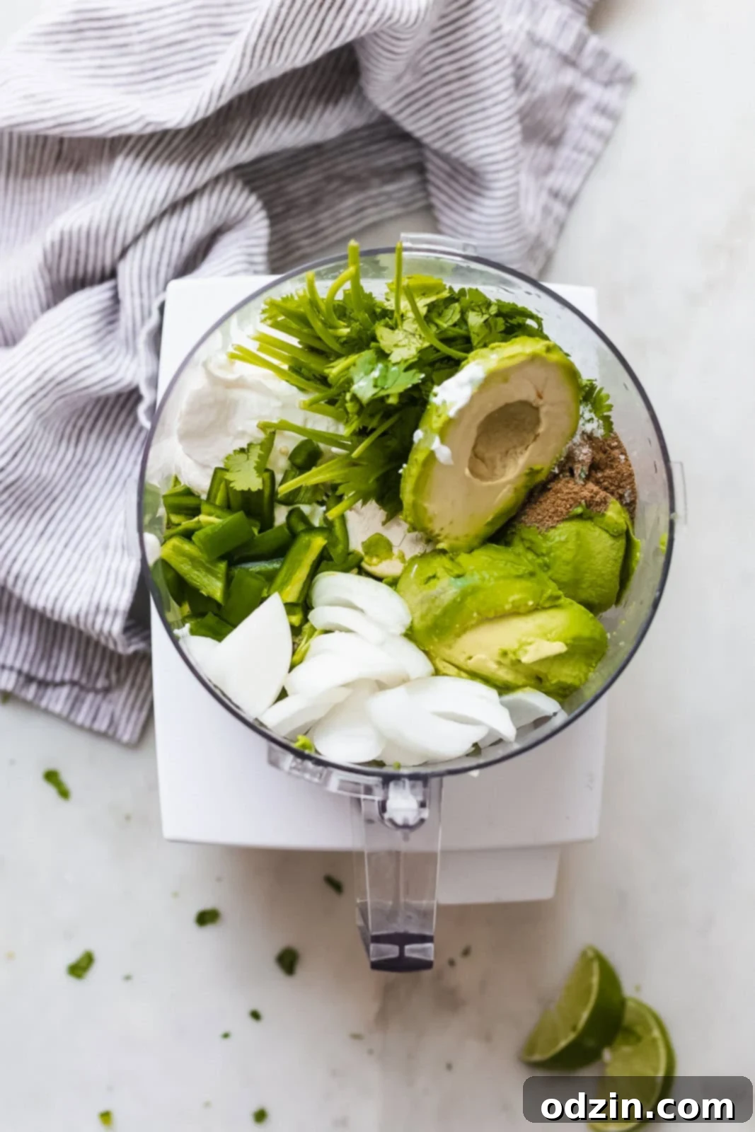 Velvety 5-Minute Avocado Dip 4 A vibrant collection of fresh ingredients like avocados, sour cream, white onions, cilantro, lime, garlic, and cumin ready to be blended into a creamy avocado dip.