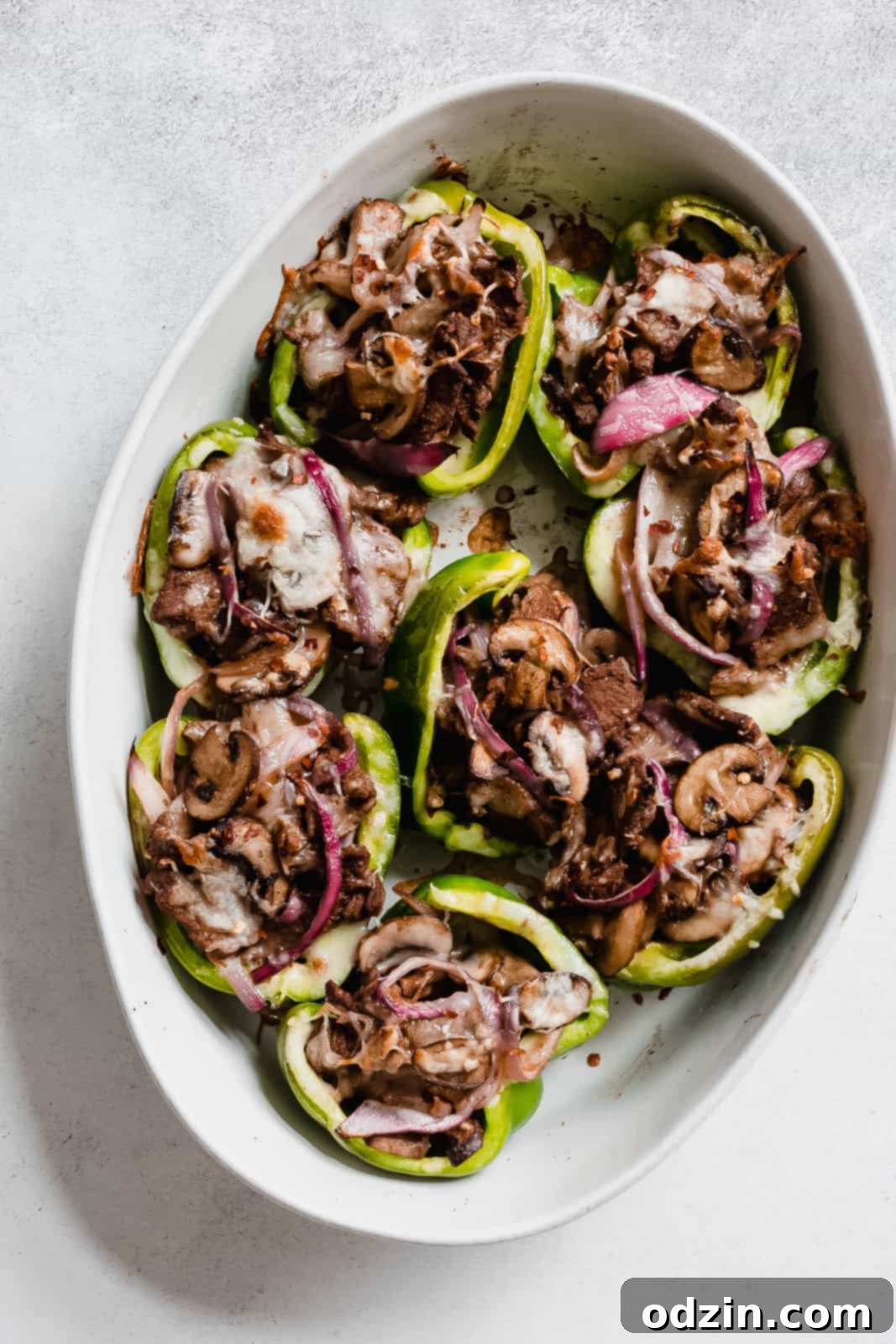 oval dish with green bell peppers stuffed with Philly cheese steak mixture
