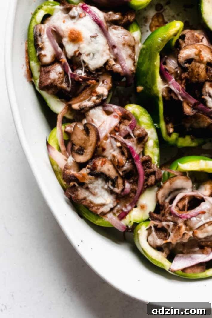 close up of peppers in dish stuffed with mushrooms, steak, and onions, topped with cheese