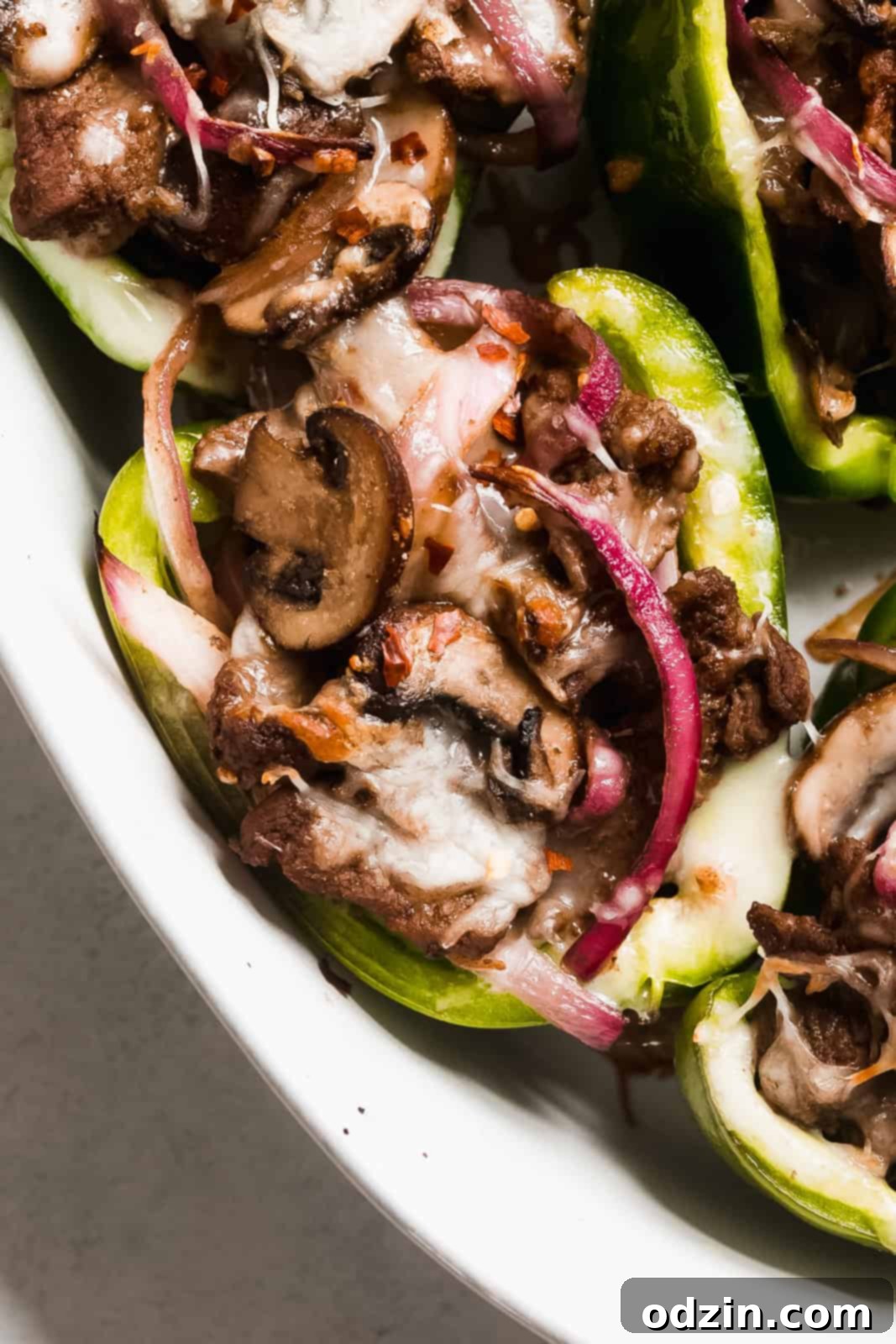 close up of colorful pepper with red onions, melted cheese, and sautéed mushrooms