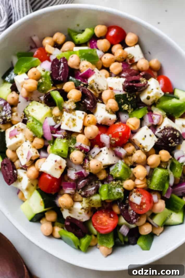 Marinated Feta Greek Salad - this is the best greek salad ever! It starts with feta that you marinated in olive oil with a few herbs and spices, then we'll toss it all together in a bowl with a homemade vinaigrette. Trust me, you'll never want a regular greeksalad again! #marinatedfeta #greeksalad #authenticgreeksalad #fetasalad #salad #saladrecipes | Littlespicejar.com close up of greek olives, feta cheese, bell peppers, chickpeas, and lemon dressing