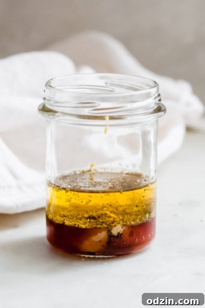 Marinated Feta Greek Salad - this is the best greek salad ever! It starts with feta that you marinated in olive oil with a few herbs and spices, then we'll toss it all together in a bowl with a homemade vinaigrette. Trust me, you'll never want a regular greeksalad again! #marinatedfeta #greeksalad #authenticgreeksalad #fetasalad #salad #saladrecipes | Littlespicejar.com ingredients for greek salad dressing in glass jar before shaking