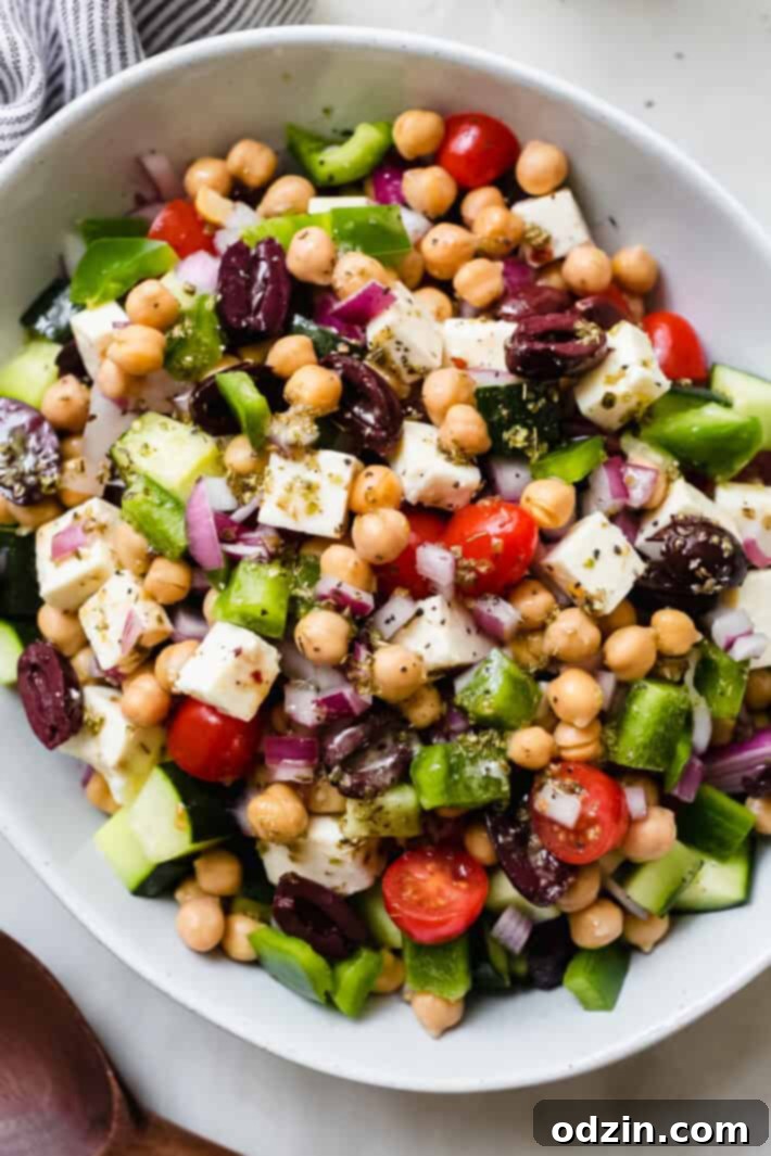 Marinated Feta Greek Salad - this is the best greek salad ever! It starts with feta that you marinated in olive oil with a few herbs and spices, then we'll toss it all together in a bowl with a homemade vinaigrette. Trust me, you'll never want a regular greeksalad again! #marinatedfeta #greeksalad #authenticgreeksalad #fetasalad #salad #saladrecipes | Littlespicejar.com close up of marinated feta in a bowl full of greek salad