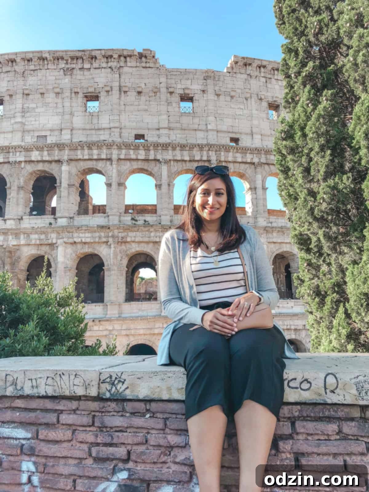 me sitting on the wall with the Colosseum behind me