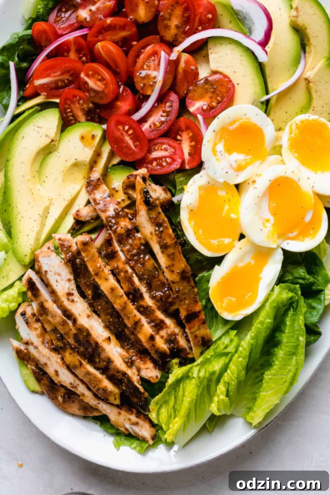 Close-up shot of the colorful ingredients for Cobb salad arranged artfully on a plate, highlighting freshness.