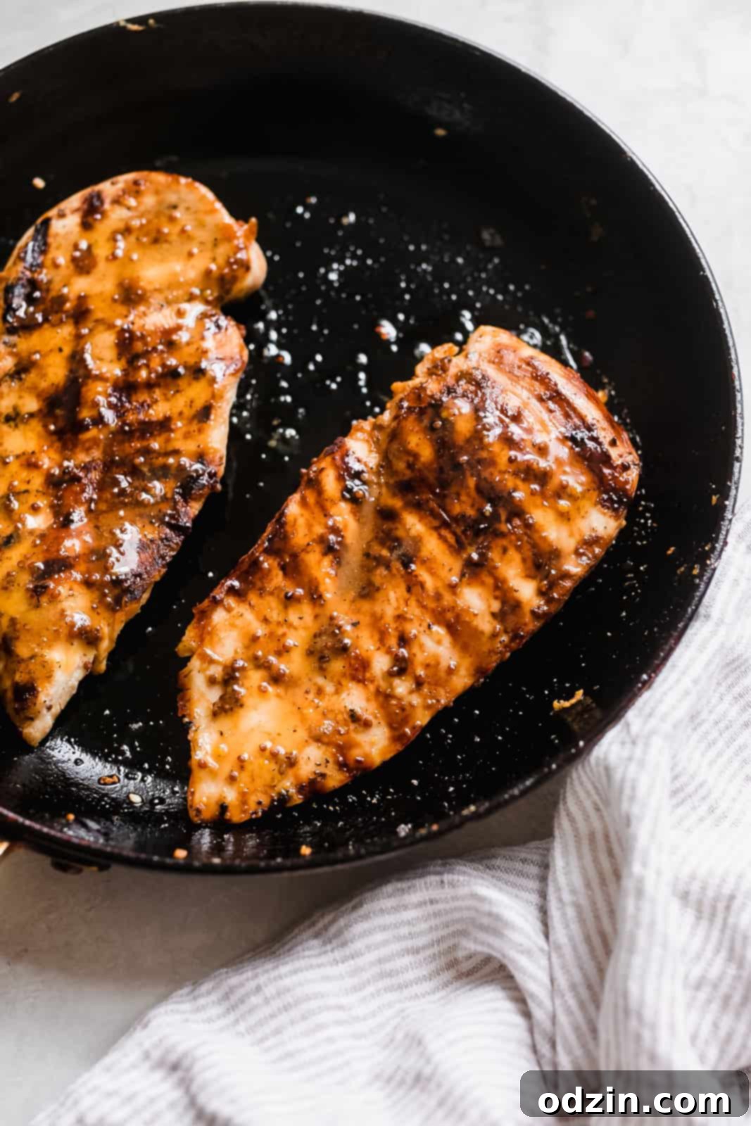 Seared honey mustard chicken breasts glistening in a nonstick frying pan, cooked to perfection.