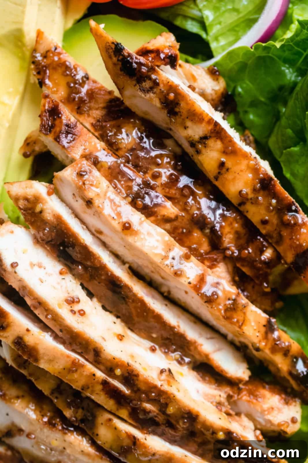 Perfectly sliced honey mustard chicken, showing its juicy interior, ready to be added to the salad.