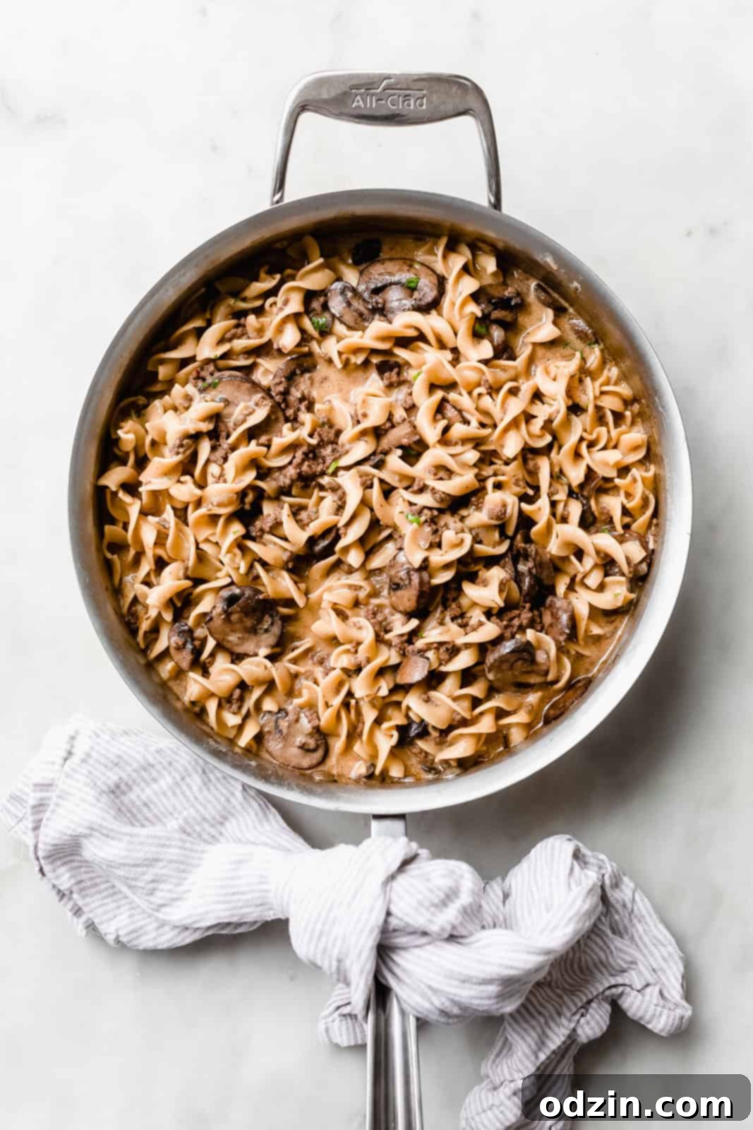 saute pan with prepared egg noodles in brown gravy sauce, mushrooms, and ground beef