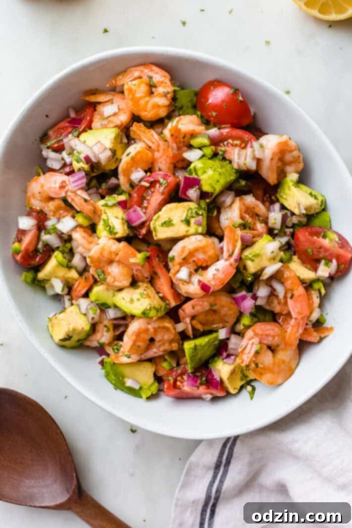 bowl of prepared Mexican shrimp salad, garnished with fresh cilantro and lime wedges