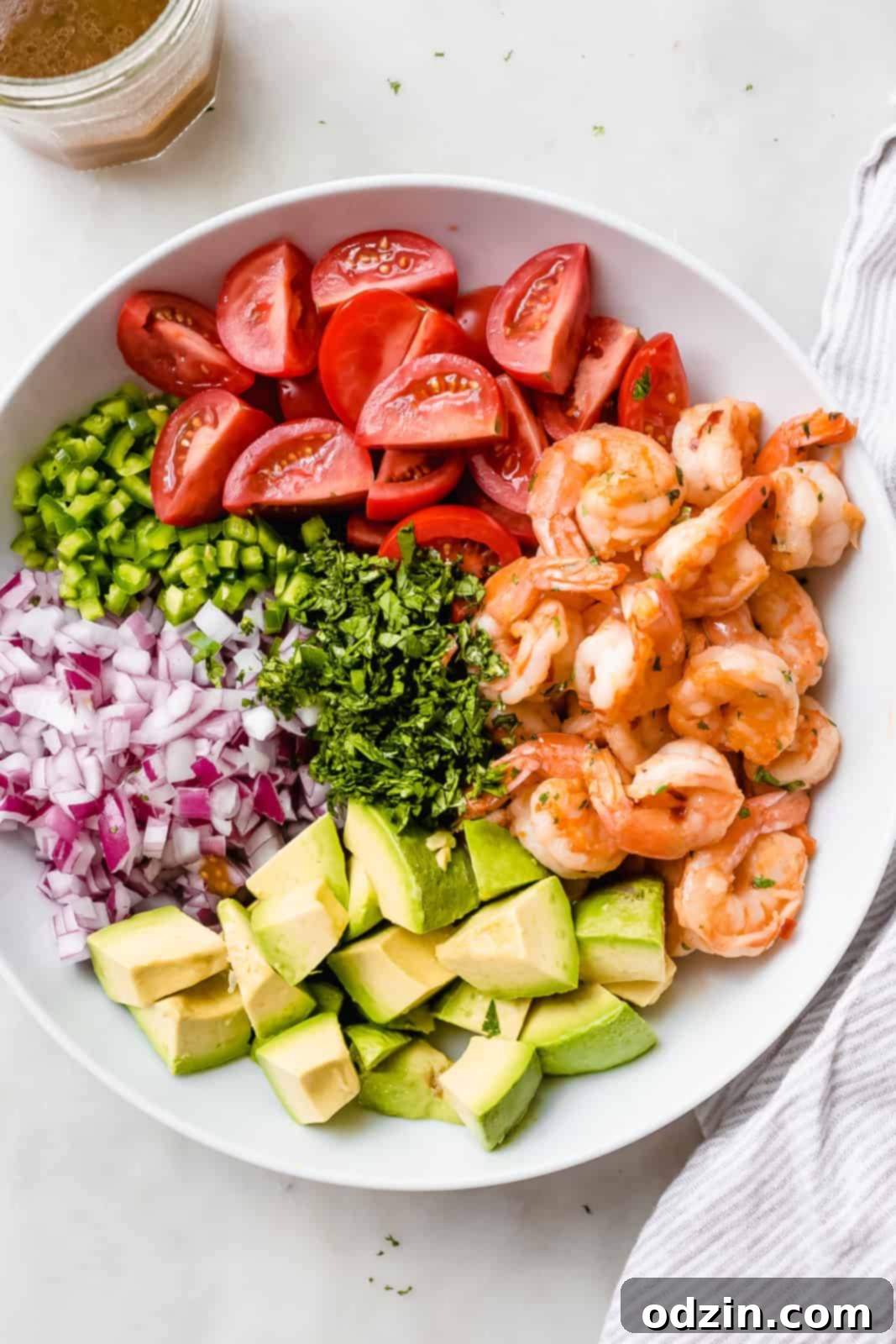 ingredients for Mexican shrimp salad carefully arranged in piles in a large white bowl, ready for mixing