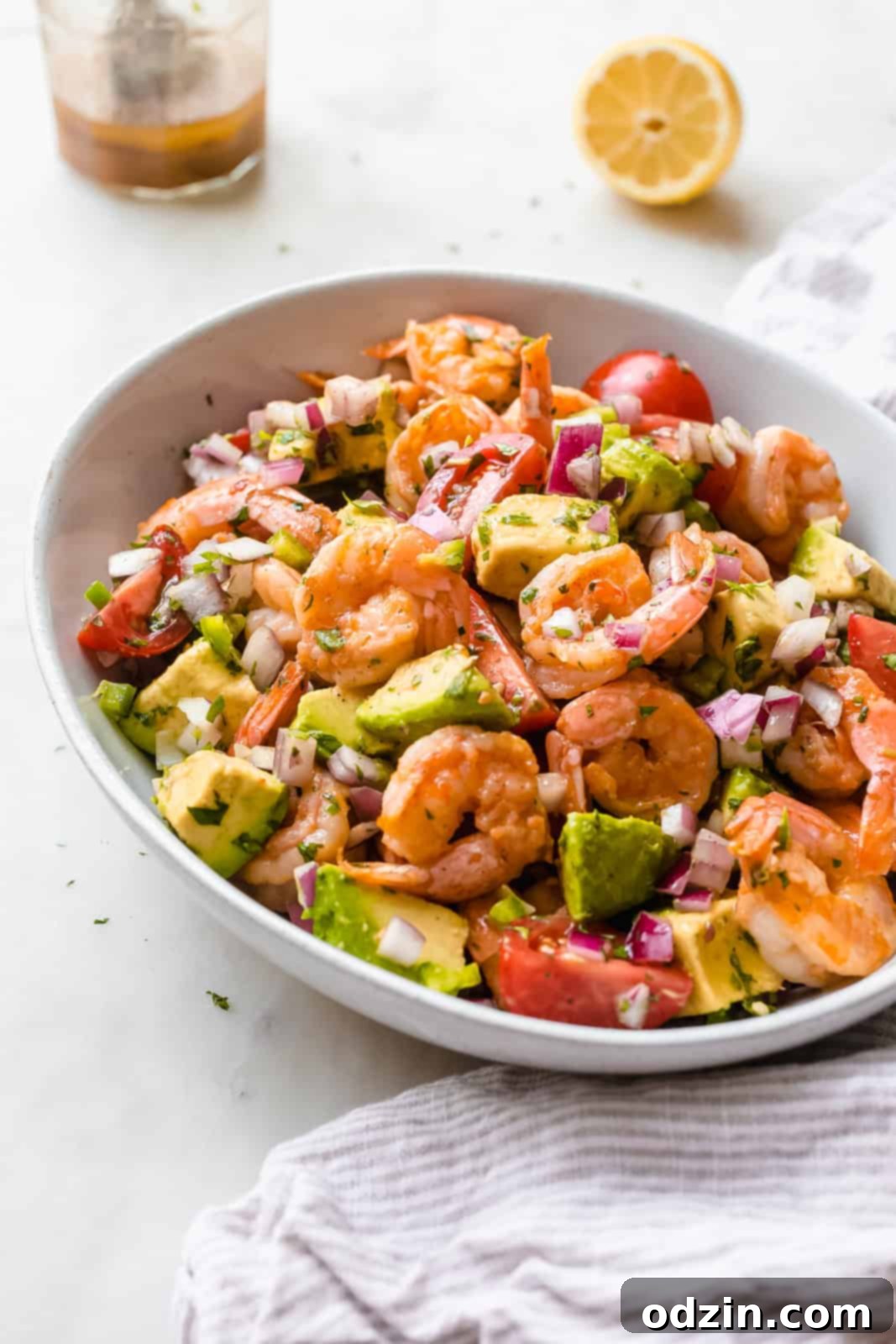 angled view of a vibrant shrimp salad with creamy avocados, beautifully dressed in a zesty lemon dressing