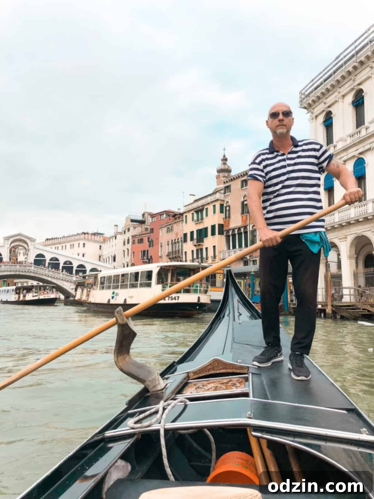 a picture of our gondolier with the Rialto bridge behind him