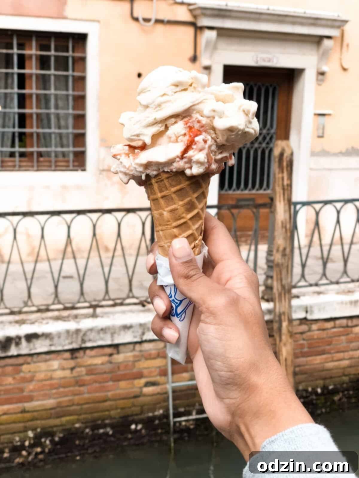 a large scoop of strawberry cheesecake gelato on a cone