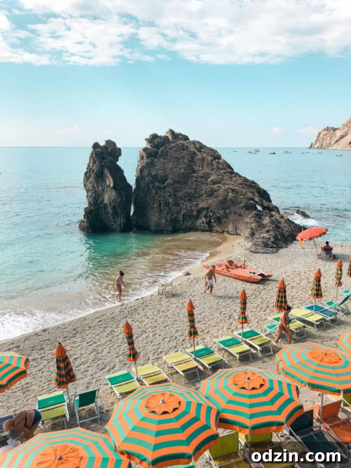the beach at Monterosso al Mar with orange and teal umbrellas all along the beachside